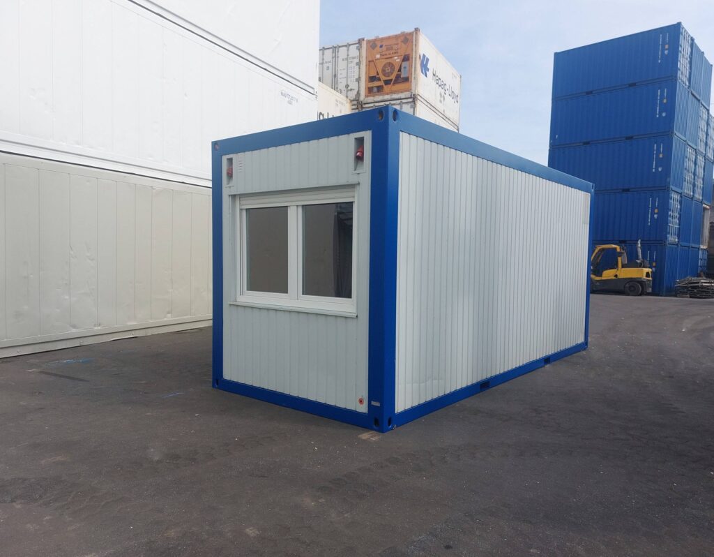 Ein 20 Fuß langer Bürocontainer, der hauptsächlich hellgrau ist, wird von einem blauen Rahmen eingefasst. Auf einer Seite befindet sich ein Fenster.