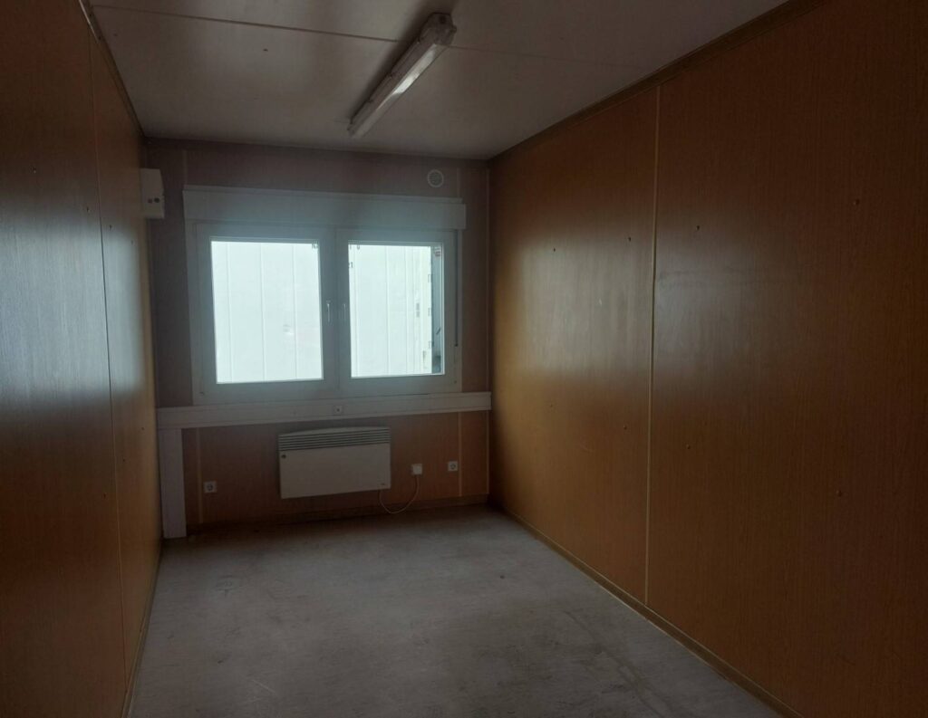 Holzverkleideter 20 Fuß Bürocontainer in brauner Farbe mit einem großen Fenster, Heizkörper und Deckenleuchte.