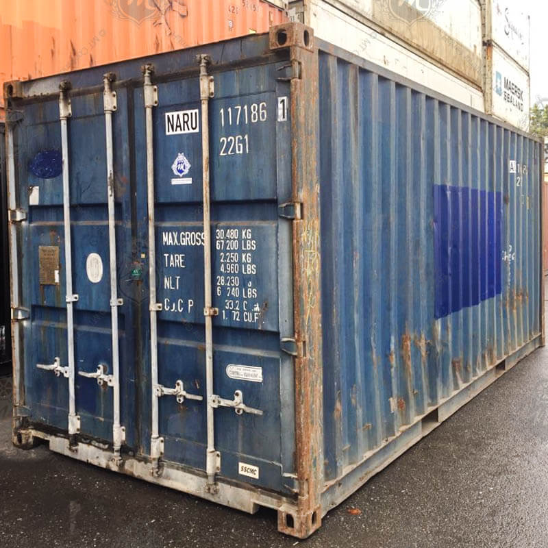 Ein blauer 20-Fuß-Seecontainer mit der Kennung NARU 117186-1 steht auf einem Asphaltboden, der Container ist rechteckig und aus Metall.