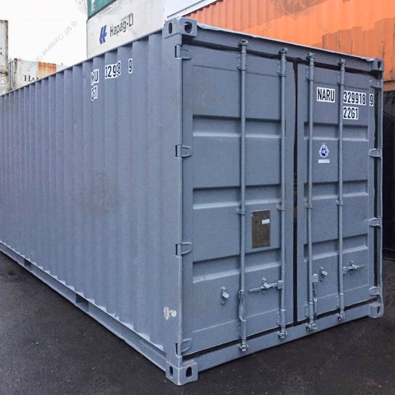 Ein grauer, 20 Fuß langer Seecontainer mit der Kennzeichnung "NARU 329918-9" steht direkt auf einer asphaltierten Fläche, Türseite sichtbar.