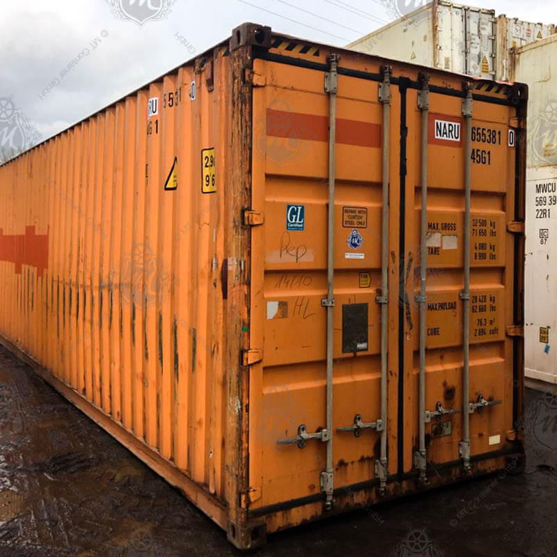 Ein orangefarbener 40 Fuß High Cube Seecontainer mit der Aufschrift "NARU 655381-0" steht aufrecht mit verschlossenen Türen.