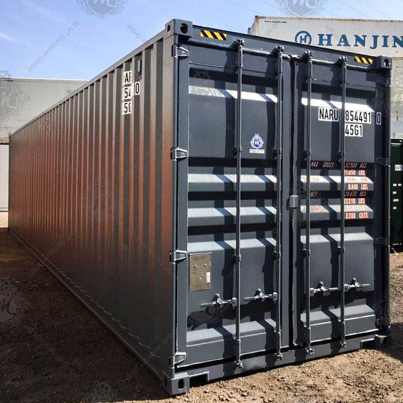 Ein grauer 40 Fuß High Cube Seecontainer mit der Aufschrift "NARU 854491-0" steht auf einem unbefestigten Boden. Der Container hat doppelte verriegelte Türen.