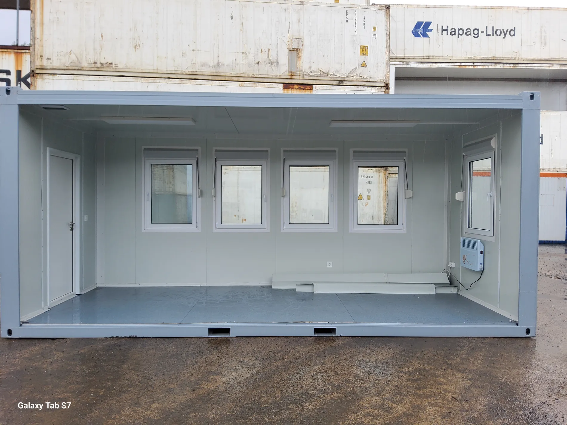 Bürocontainer in Grau mit geöffneter Längsseite, Blick auf Innenraum, Fenster und Heizung