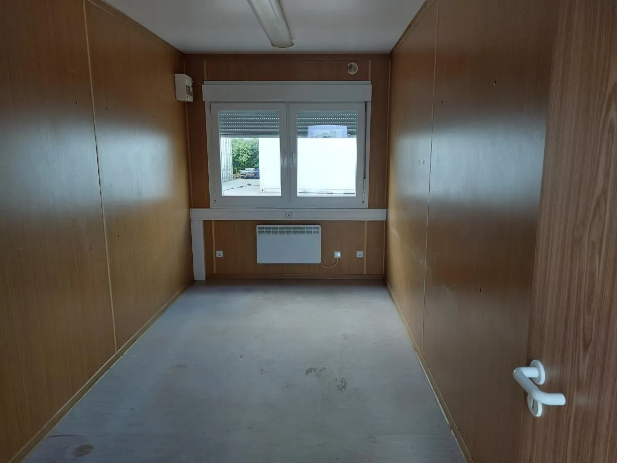 Innenraum eines Bürocontainers mit Holzdekor-Wandverkleidung, Fenster und Elektroheizung