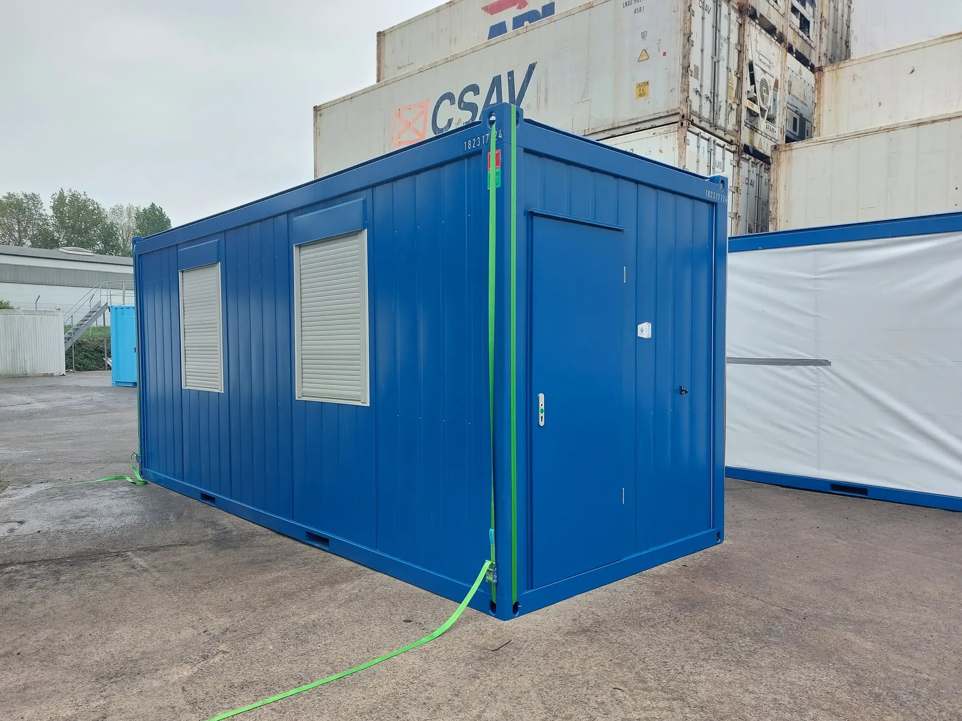 Neuer 20-Fuß-Bürocontainer in Blau mit Eingangstür und zwei Rollladenfenstern