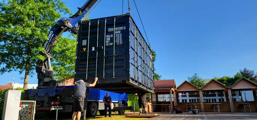 Kran setzt den Stahlcontainer für den Biergarten ab